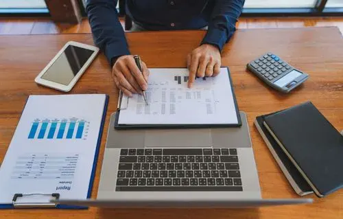 Relatórios contábeis, notebook e calculadora sobre a mesa