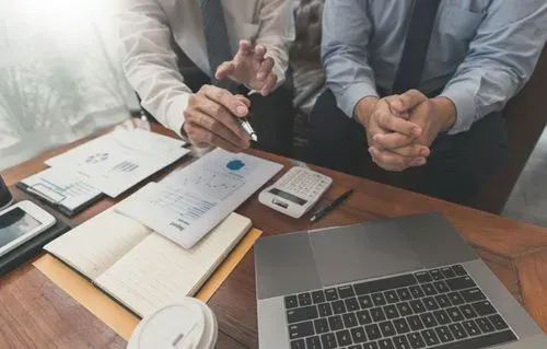 Reunião de análise de documentos fiscais com calculadora e notebook